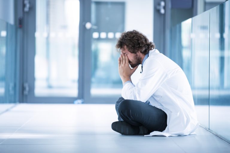 Worried doctor sitting on floor